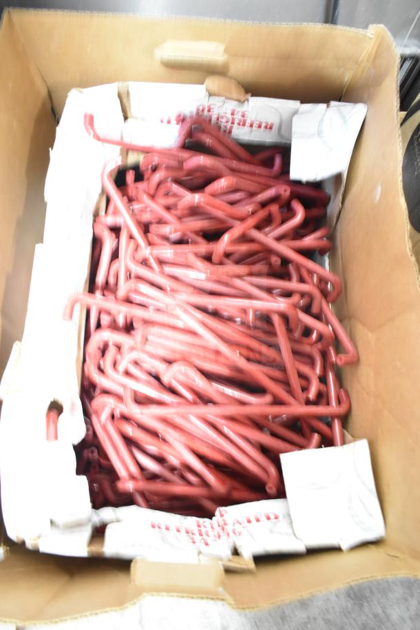Lot of red metal hooks in a cardboard box, part of a four-box auction lot. Hooks appear new and unmarked.