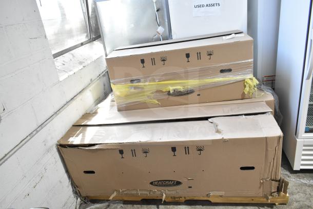 Three Heatcraft boxes stacked, containing new Bohn BEL0650AG6AMAD2107 and BEL0130CC6EEAYF859 evaporator fans, with minor damage.