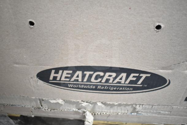 Heatcraft branded cardboard box with visible tear, containing scratch and dent items. Brand logo says "Worldwide Refrigeration."