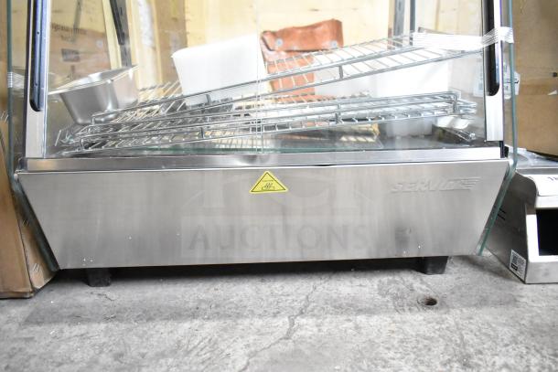 BRAND NEW ServIt 423HDM26SA 26" heated display case with sliding doors, 3 shelves, 120V. Caution label visible.