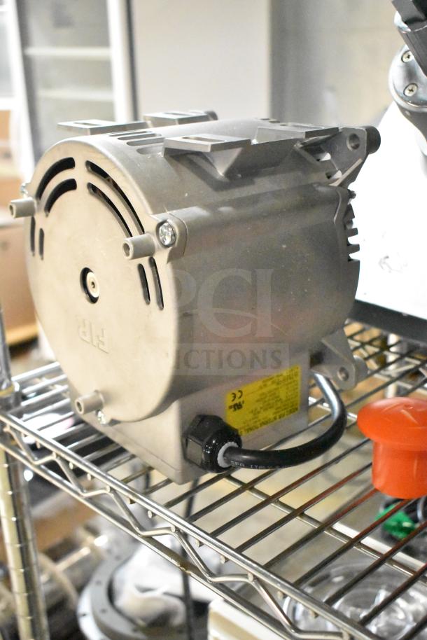 Brand new 2025 Nidec motor, 230 volts, minor scratches and dents, visible yellow label, resting on a metal shelf.