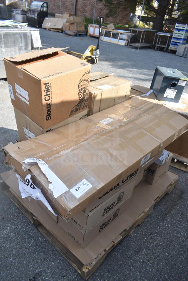 Cardboard boxes on a pallet with Sioux Chief branding, containing new scratch and dent items, including tube hangers and brackets.