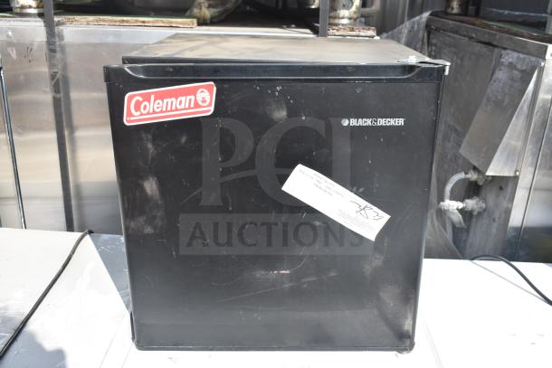 Black & Decker mini cooler with Coleman sticker, visible wear, placed outdoors.
