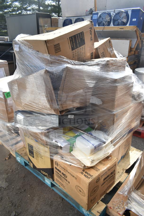 Stack of boxes on a pallet, wrapped in plastic. Boxes labeled for cups, tumblers, and envelopes, showing scratch and dent items.