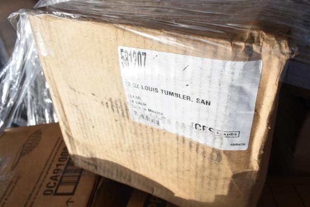 A box labeled "12 oz Louis Tumbler, SAN" with signs of wear, wrapped in clear plastic, indicating a scratch and dent sale.