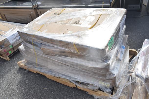 Seven brand new scratch and dent tabletop and outdoor tables, wrapped on a pallet with visible item labels.