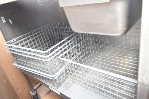 Commercial counter with drawer, under shelf, and wire baskets; includes visible metal surfaces and storage space.