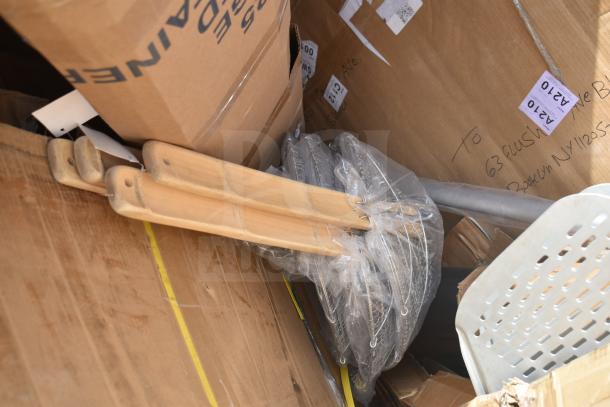 A box containing brand new pizza peels, metal table base pieces, and other items. Some items have minor scratches and dents.