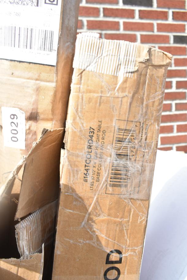 Cardboard boxes labeled "#164TCOLD437," containing new pizza peels and table base pieces, showing signs of wear.