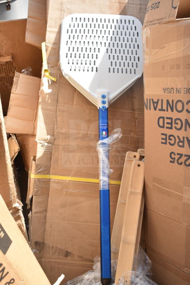 Brand new pizza peel with blue aluminum handle next to cardboard boxes, includes other assorted items. Scratch and dent condition.