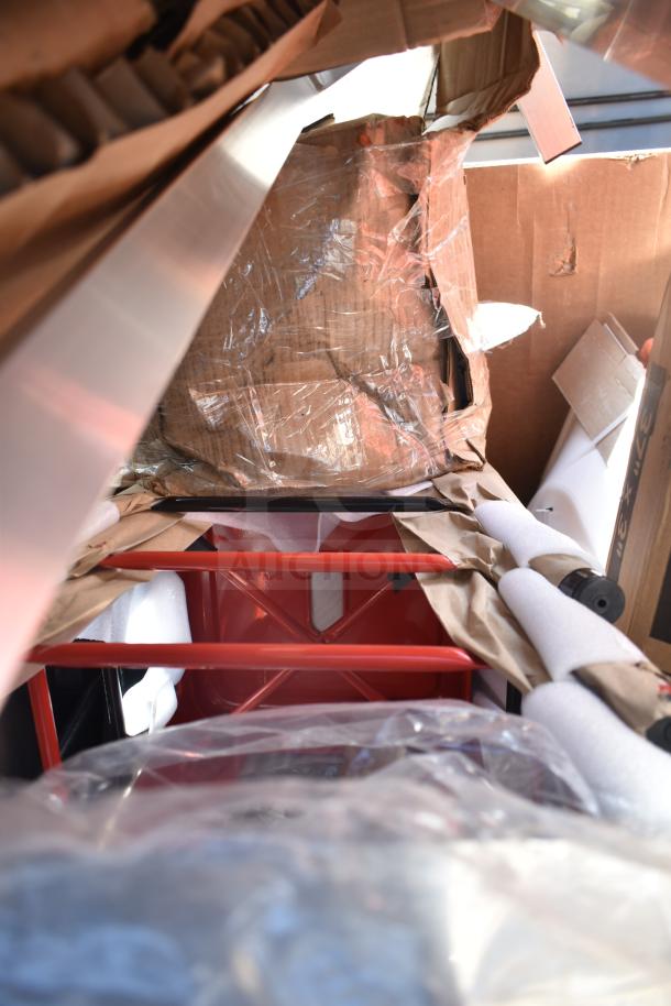 Boxes of brand new scratch and dent items, including a red table and sink, wrapped in packaging materials.