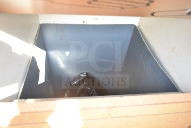 Trash can shell with trash deposit hole and door, featuring a durable interior and a black trash bag.