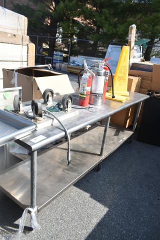 Commercial table with fire extinguishers, dolly, and caution sign. Metal construction, visible wear. Auction lot number tag attached.