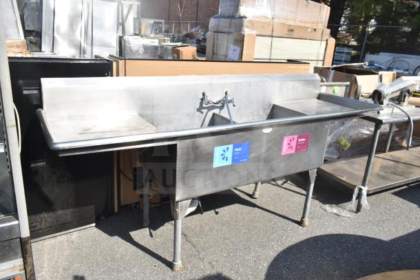 Commercial 2 bay sink with dual drain boards, stainless steel, pre-owned condition, labeled for washing and sanitizing.