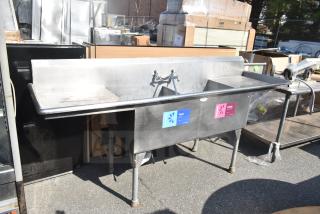Commercial 2 bay sink with dual drain boards, stainless steel, pre-owned condition, labeled for washing and sanitizing.