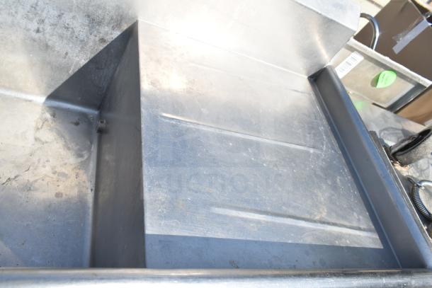 Commercial 2 bay sink with dual drain boards, showing stainless steel construction and some surface wear, ideal for kitchens.