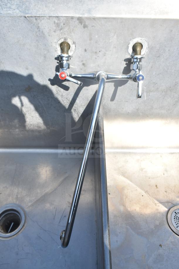 Commercial 2 bay sink with dual drain boards, stainless steel, wall-mounted faucet, slight wear, ideal for kitchens.