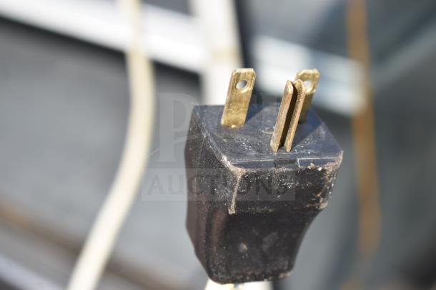 Close-up of a three-prong plug from a Commercial Grab N Go Merchandiser, showing signs of wear.