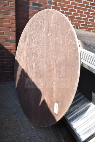 Round folding table, wood finish, leaning against a brick wall. Visible scuffs, auction tag number 266.