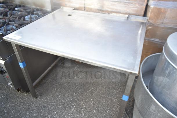 Stainless steel commercial table with sturdy legs, in good condition, minor surface wear. Ideal for kitchen use.