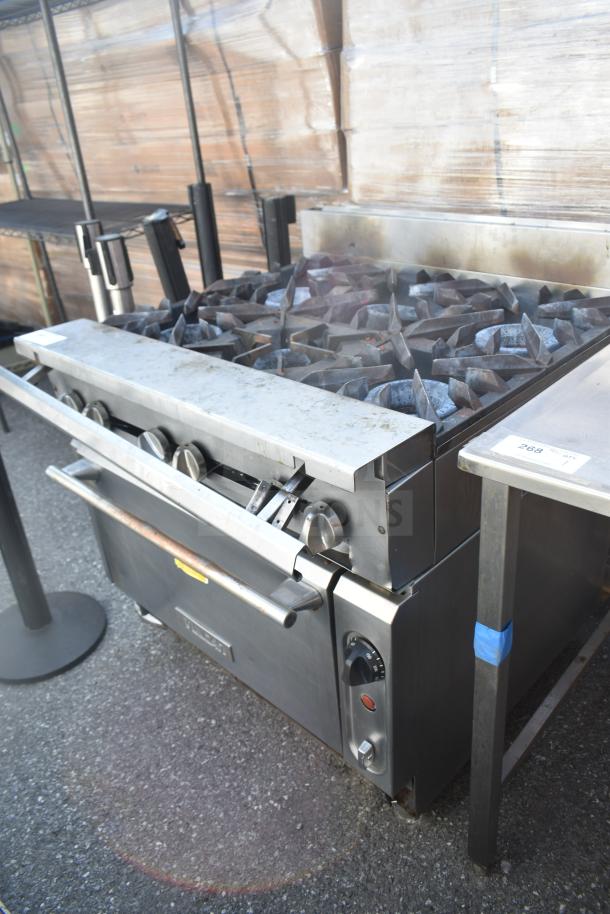 Vulcan commercial gas range with 6 burners and oven. Stainless steel, used condition, visible control knobs and handles.