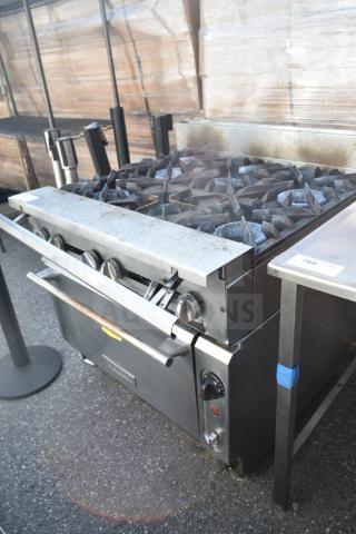 Vulcan commercial gas range with 6 burners and oven. Stainless steel, used condition, visible control knobs and handles.