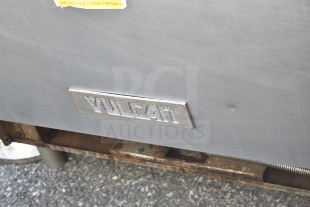 Vulcan commercial gas-powered 6 burner range with oven; features Vulcan branding and visible wear on exterior.