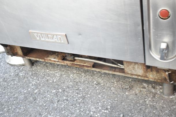 Vulcan commercial gas-powered 6-burner range with oven. Stainless steel with visible wear and Vulcan nameplate.