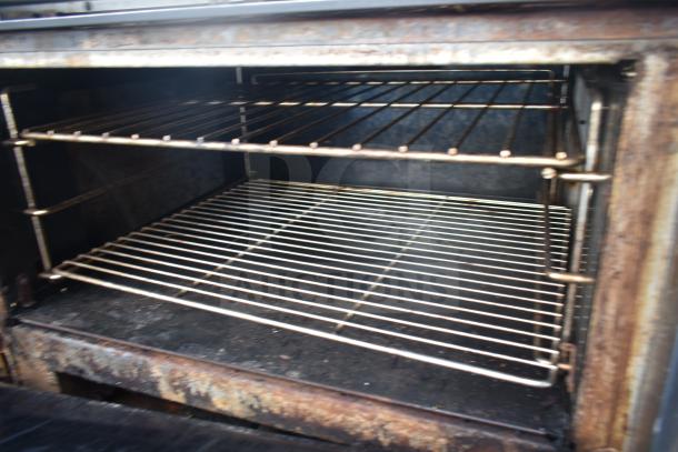 Vulcan commercial gas 6 burner range with oven, interior view. Visible racks, good condition. Ideal for restaurant use.