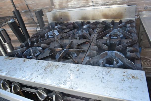 Vulcan commercial gas-powered 6 burner range with oven, showing visible wear and residue on stovetop and control knobs.