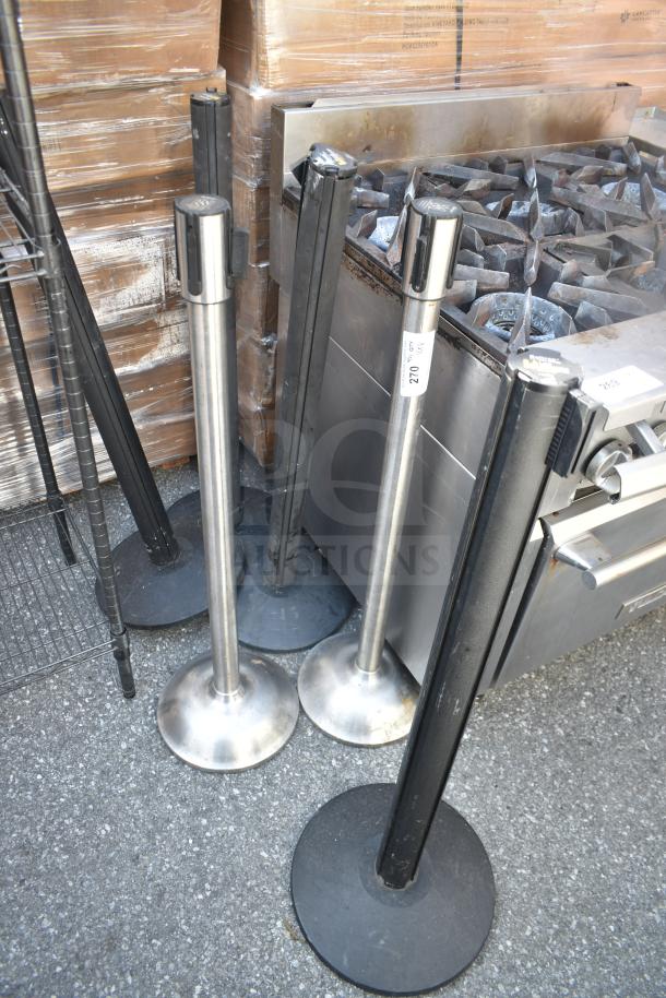Six metal stanchions with weighted bases, mixed silver and black finish, visible wear. Auction includes all six.
