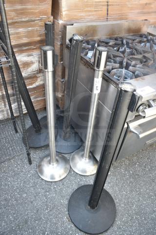 Six metal stanchions with weighted bases, mixed silver and black finish, visible wear. Auction includes all six.