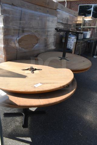 Four round wooden tables stacked, one missing a base. Visible wear, auction lot number 205. Includes three black bases.