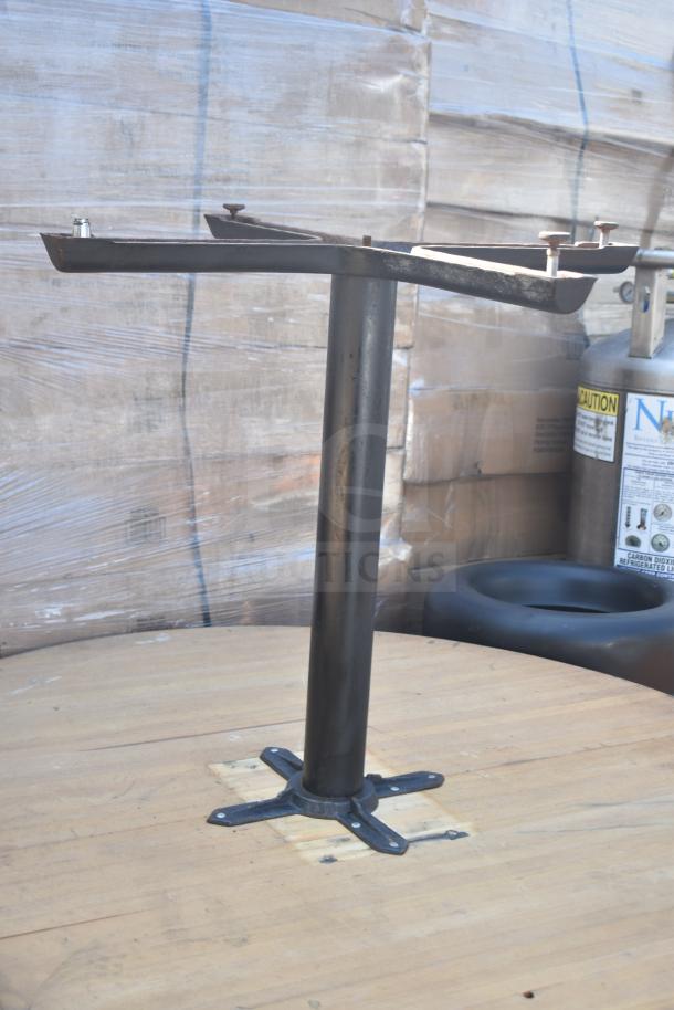 Metal table base missing one leg, placed on wooden surface. Condition appears used. Auction lot of four tables.