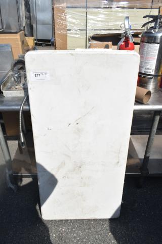 White folding table with a rectangular shape, showing minor scuffs and dirt. Auction tag labeled "277" attached.
