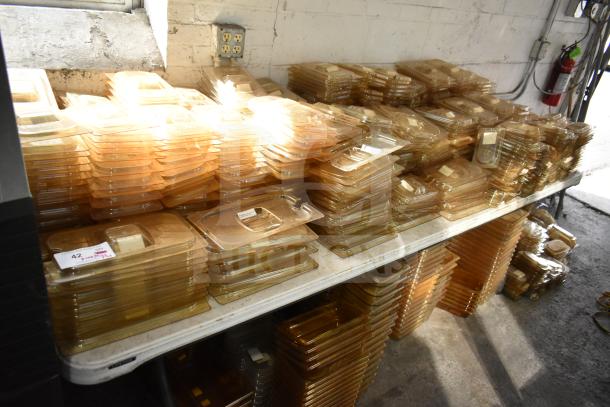 Brand new lot of amber drop-in bin lids, FG202P22AMBR, FG221P86AMBR. Includes tabletop and floor items, neatly stacked.