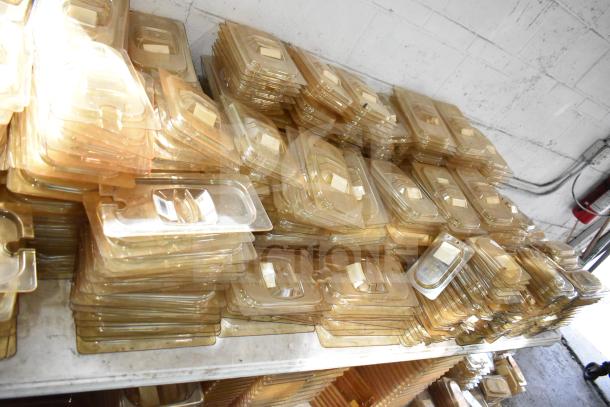 Lot of new amber-colored drop-in bin lids, models FG202P22AMBR, FG221P86AMBR, tabletop and floor items stacked.