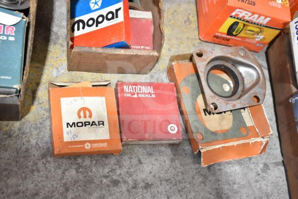 Lot of various auto parts including Fram PH4967 Extra Guard, Napa thermostat, Mopar components, and towel bars. Boxes show wear.