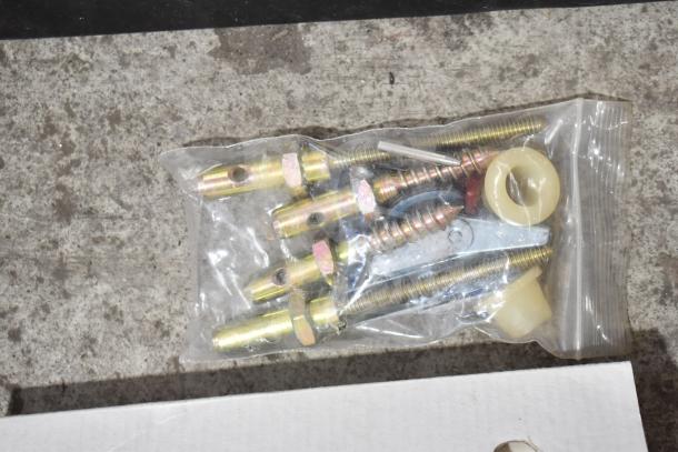 Bag of assorted screws, bolts, and anchors sealed in clear plastic on a concrete surface.