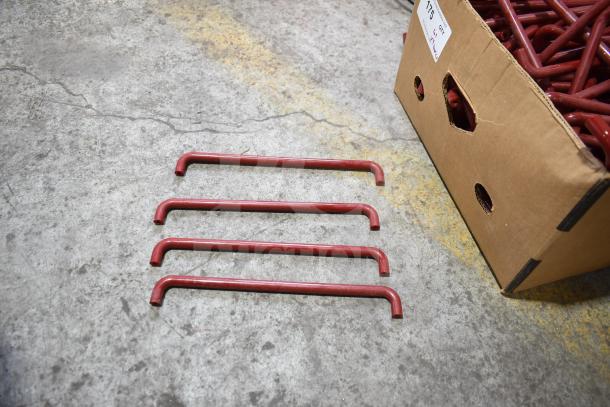 Lot of 4 red metal handles, curved, beside a cardboard box, items in good condition, visible auction label.