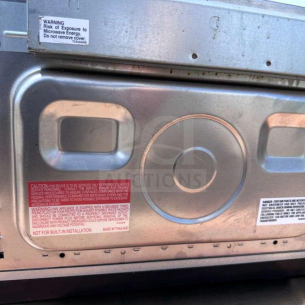 Sharp R-21LCFS commercial microwave back view showing caution labels, stainless steel exterior, and ventilation details.