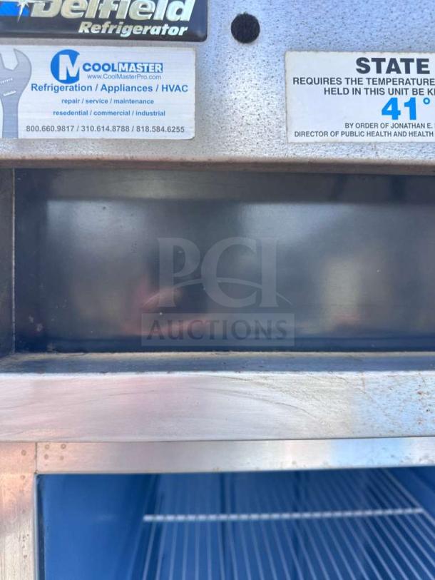 Delfield 6025XL-S refrigerator, stainless steel, commercial single-section, tags indicating model and temperature compliance.