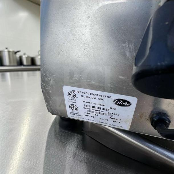 Elite condition Globe G12 12" commercial meat slicer, 1/2 HP. Heavy-duty, gravity feed, fully operational, with ETL certification label.