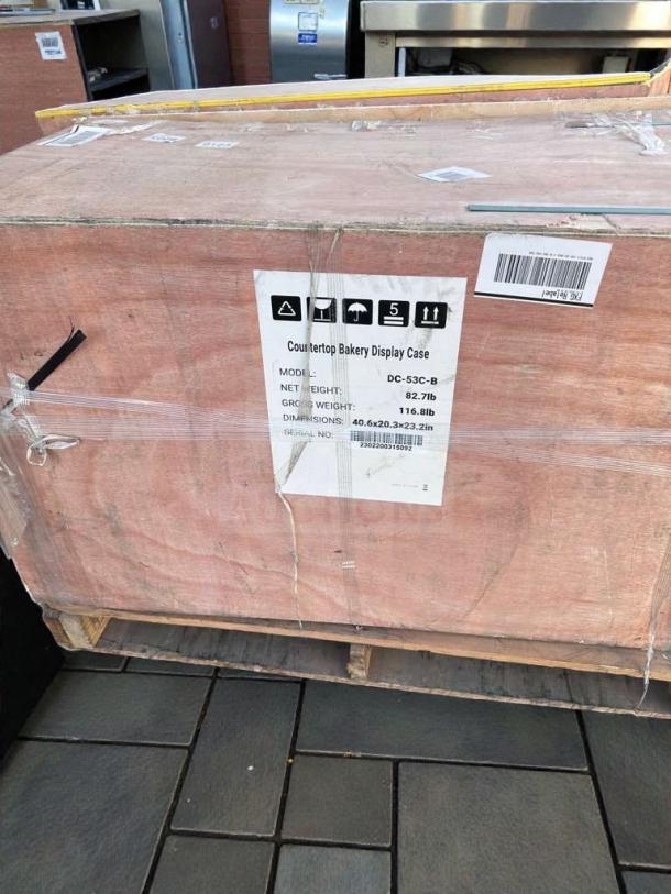Brand new KoolMore DC-53C-B countertop bakery display case in original crate. Model and weight details visible on label.