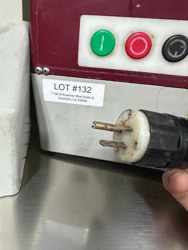 Commercial food processor control panel with power buttons and plug. Label reads "LOT #132, 1130 N Kraemer Blvd, Anaheim, CA 92806."