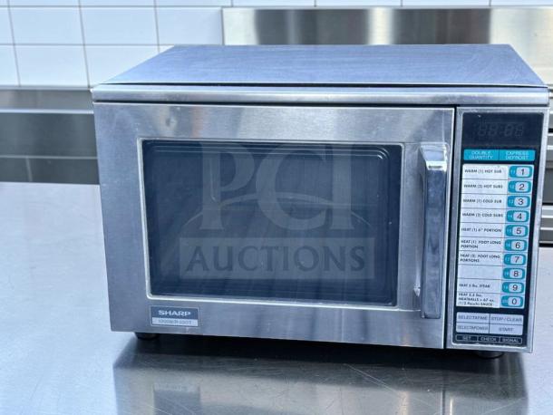 Sharp R-22GT commercial microwave oven, 1200W, stainless steel, superb condition, tested, 120V, keypad controls visible.