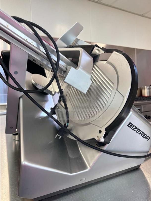 Bizerba N-22 commercial deli slicer, excellent condition, automatic, 120V, tested, Bizerba logo visible, silver finish.