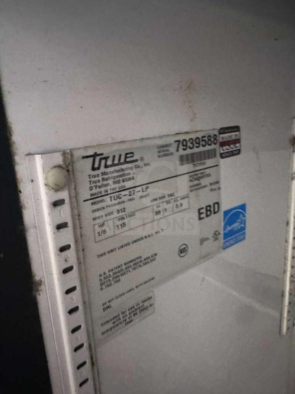 Label on True TUC-27-LP undercounter refrigerator showing model, serial number 7939588, 115V, and US manufacturing details.