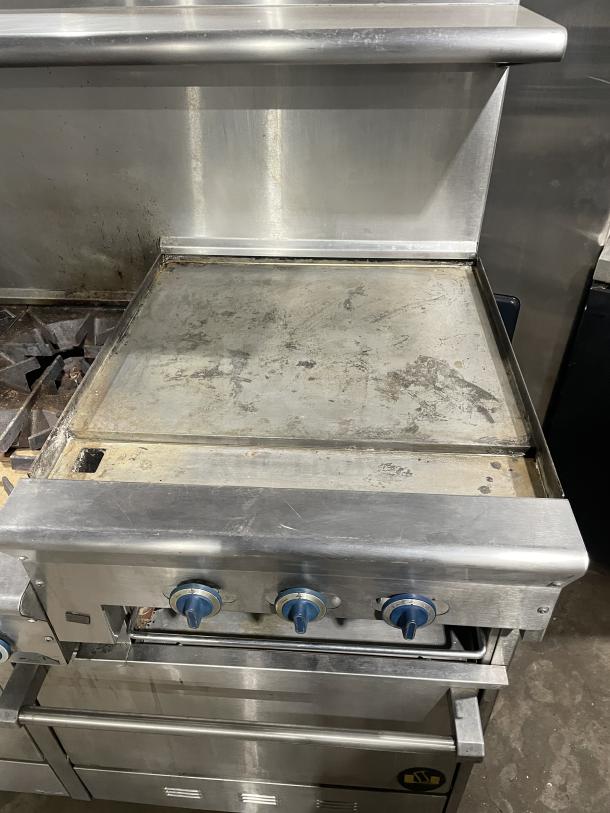 US Range stainless steel griddle/broiler, model PX-6-24BG-2626, with 6 burners, 2 ovens, and casters. Used condition.