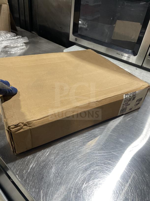 Brown shipping box for Carlisle Commercial Black 14"x18" Fast Food/Serving Tray, model NCT1418, on a metal surface.